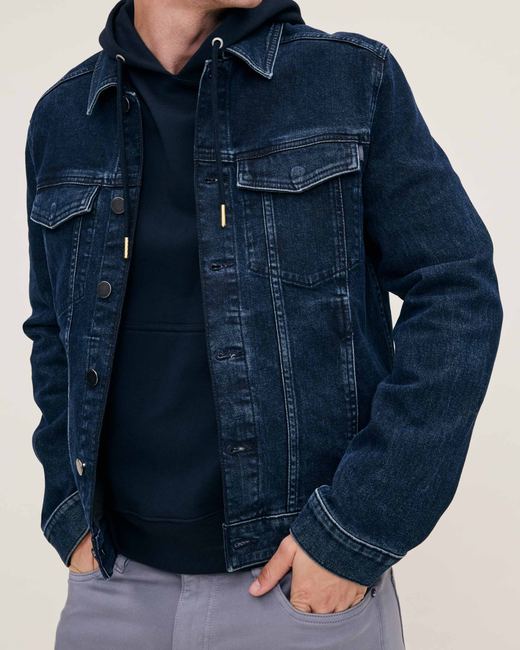 Dark indigo denim trucker jacket layered over a navy hooded sweatshirt
